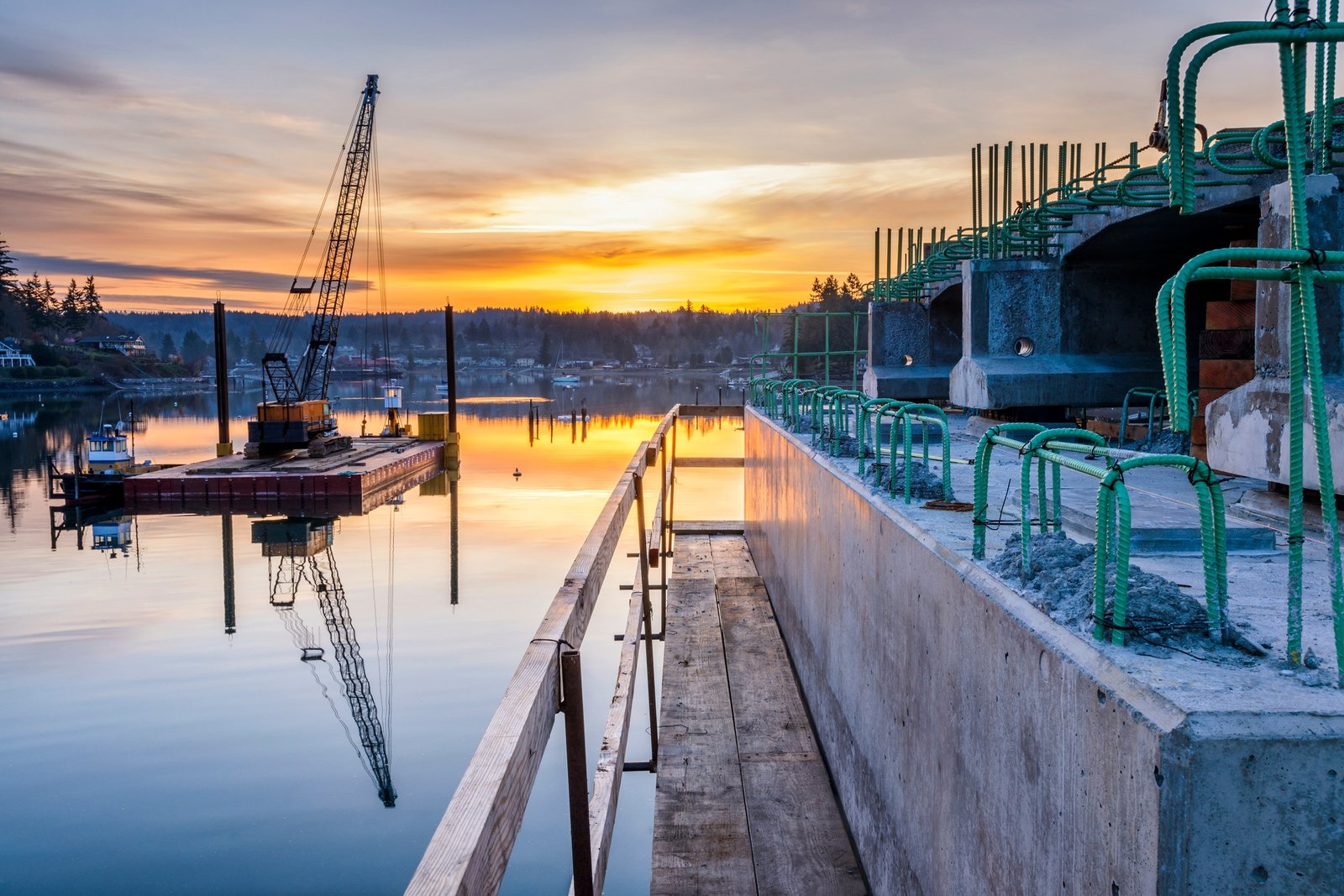 Reflection of bridge construction and sunset in still bay